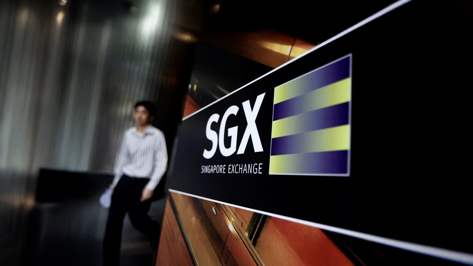 Singapore Exchange (SGX) building signage with a blurred figure in the background.