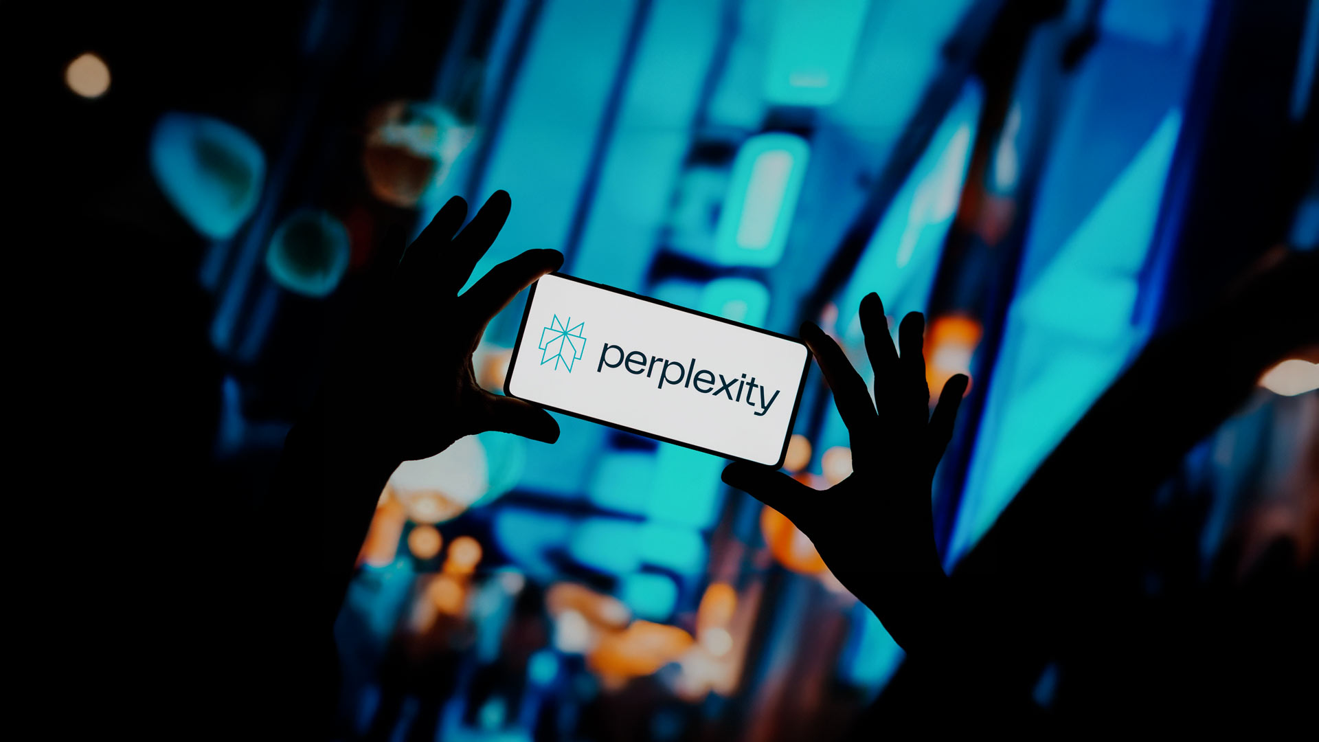 Hands holding a smartphone displaying the Perplexity AI logo against a blurred background.